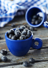 Blueberries in cup on blue wooden background