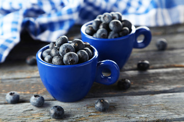 Blueberries in cup on blue wooden background
