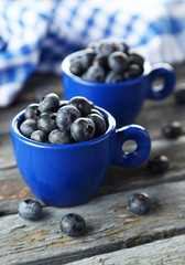 Blueberries in cup on blue wooden background