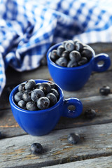 Blueberries in cup on blue wooden background
