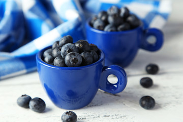 Blueberries in cup on blue wooden background