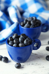 Blueberries in cup on blue wooden background