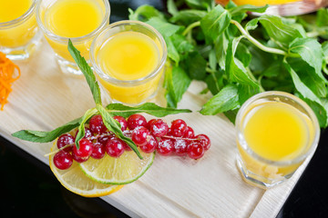 Set of several bright glasses with cold alcoholic cocktail with orange juice on a wooden table in a restaurant with ice and creative decoration of berries, fresh mint and orange slices. soft focus