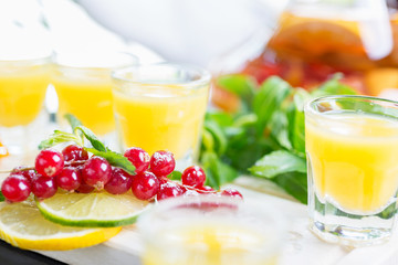 Set of several bright glasses with cold alcoholic cocktail with orange juice on a wooden table in a restaurant with ice and creative decoration of berries, fresh mint and orange slices. soft focus