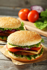 Fresh burgers on grey wooden background