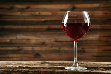Red wine glass on brown wooden background