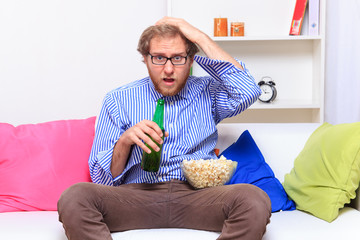 Depressed man on the sofa with popcorn and beer