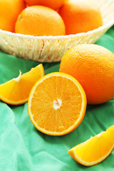 Ripe oranges in basket on green background