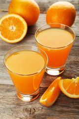 Glass of fresh orange juice on wooden background