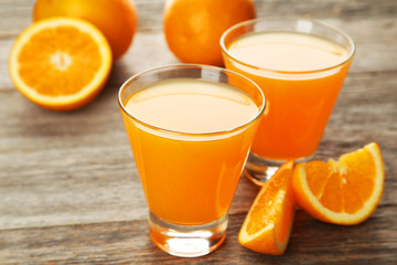 Glass of fresh orange juice on wooden background