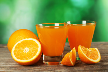 Glass of fresh orange juice on wooden background
