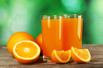 Glass of fresh orange juice on wooden background