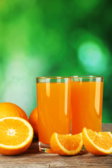 Glass of fresh orange juice on wooden background