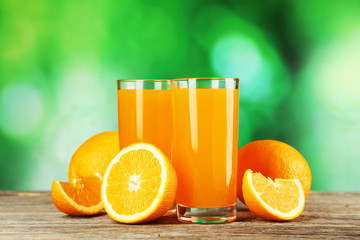 Glass of fresh orange juice on wooden background