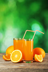 Glass of fresh orange juice on wooden background