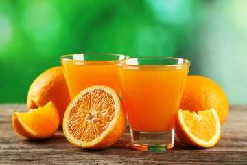 Glass of fresh orange juice on wooden background