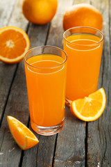 Glass of fresh orange juice on wooden background