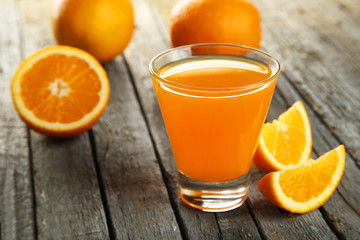 Glass of fresh orange juice on wooden background