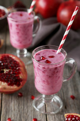 Pomegranate smoothie in glass on grey wooden background