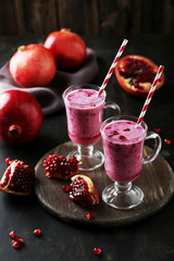 Pomegranate smoothie in glass on black background