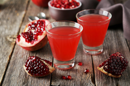 Pomegranate juice in glass on wooden background