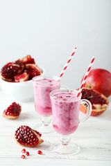 Pomegranate smoothie in glass on white wooden background