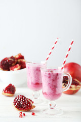 Pomegranate smoothie in glass on white wooden background