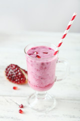 Pomegranate smoothie in glass on white wooden background