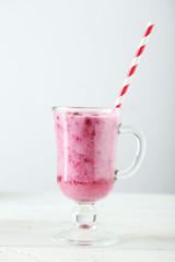 Pomegranate smoothie in glass on white wooden background