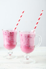 Pomegranate smoothie in glass on white wooden background
