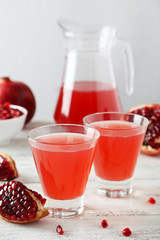 Pomegranate juice in glass on wooden background