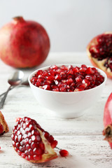 Delicious pomegranate fruit in bowl on white wooden background