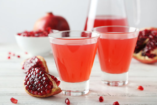 Pomegranate juice in glass on wooden background