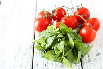 Tomatoes and basil leaves on white wooden background