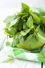 Basil leaves in bowl white wooden background