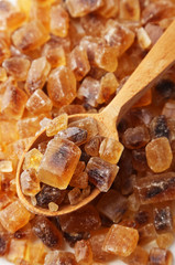 Brown sugar in spoon and bowl on wooden background