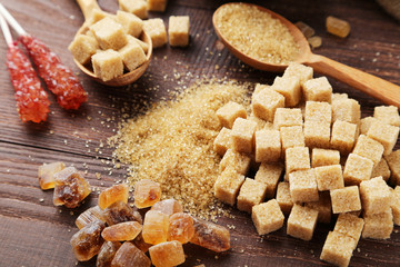 Brown sugar in spoon and bowl on wooden background