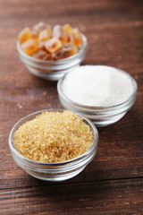 Brown sugar in spoon and bowl on wooden background