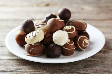 Chocolates on plate on grey wooden background