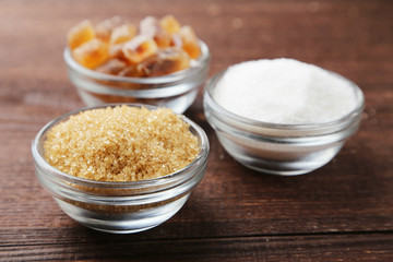 Brown sugar in spoon and bowl on wooden background
