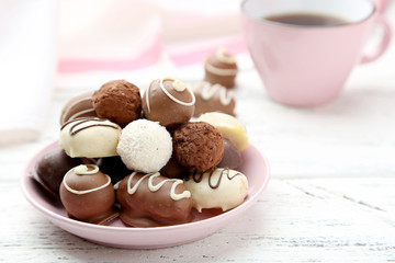 Chocolates in bowl on white wooden background