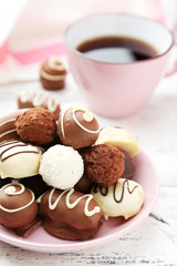 Chocolates in bowl on white wooden background