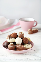 Chocolates in bowl on white wooden background