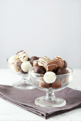 Chocolates in glass on white wooden background