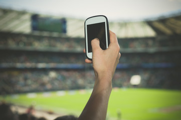 Hand filming sports event on phone
