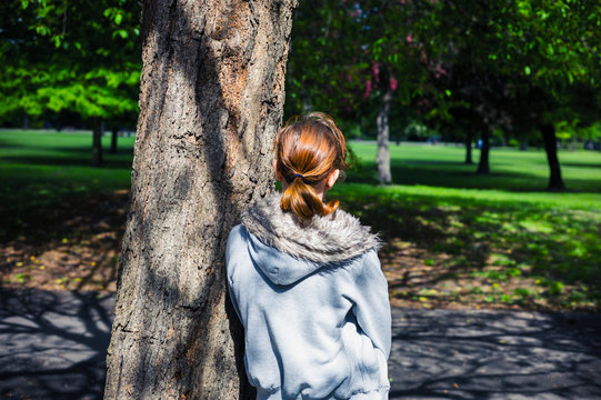 Young woman resting by tree in park