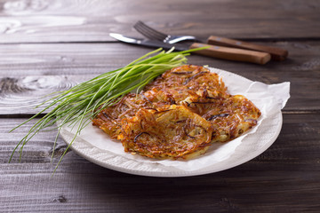 Potato fritters, green onions on a wooden surface 