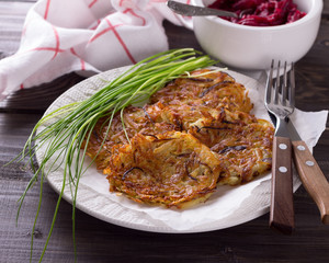 Potato fritters, beet salad, green onions on a wooden surface