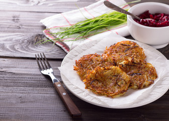 Potato fritters, beet salad, green onions on a wooden surface