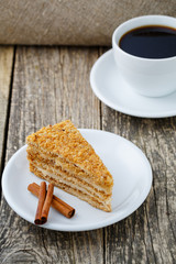 Tasty honey cake with cup of coffee on wooden background.